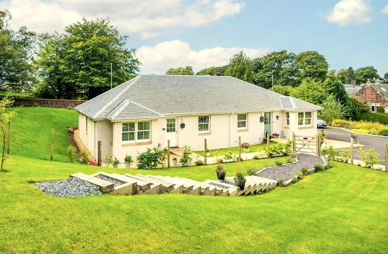 Single-storey cottage with cream render, slate roof and landscaped garden.